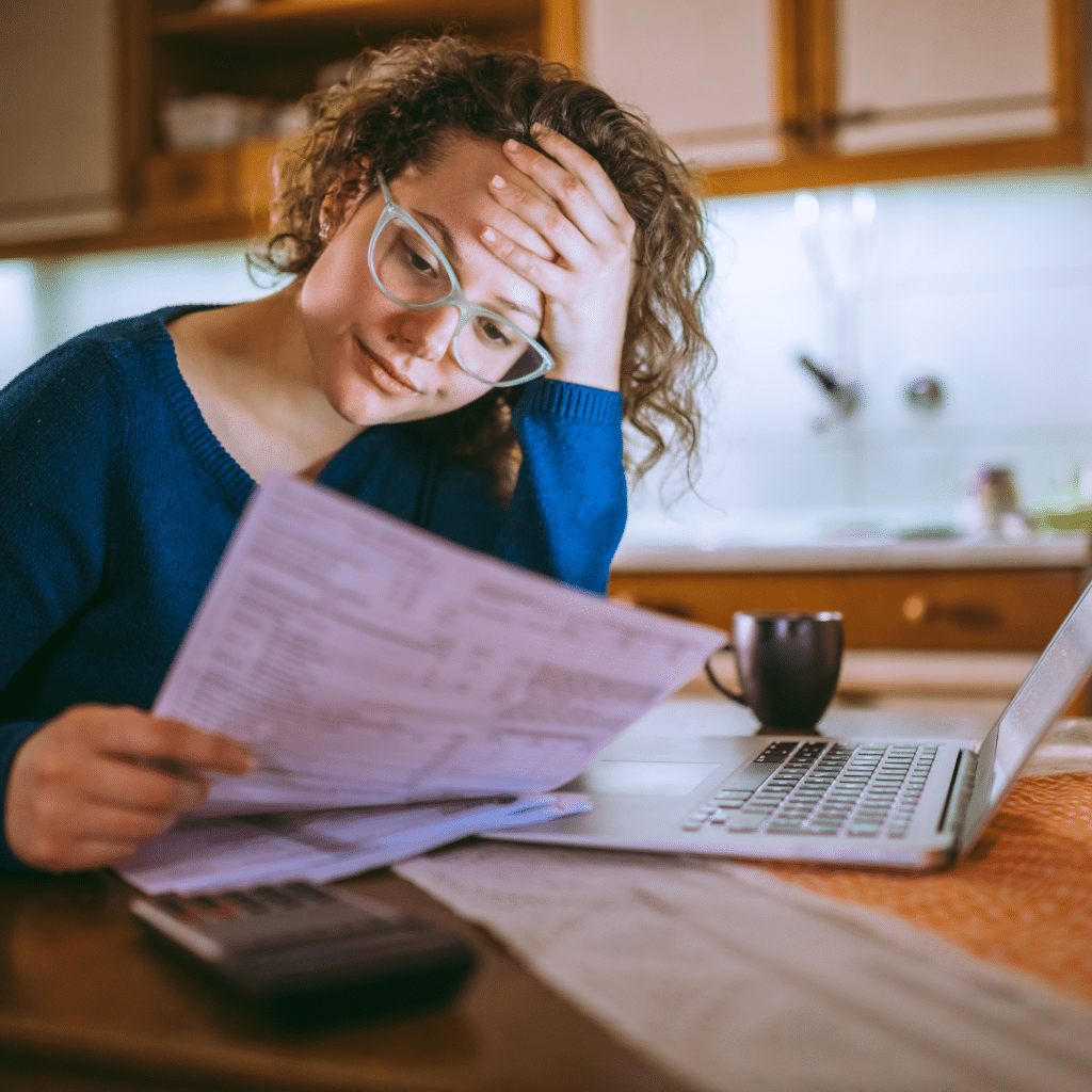 Woman holding bill and looking forlorn.