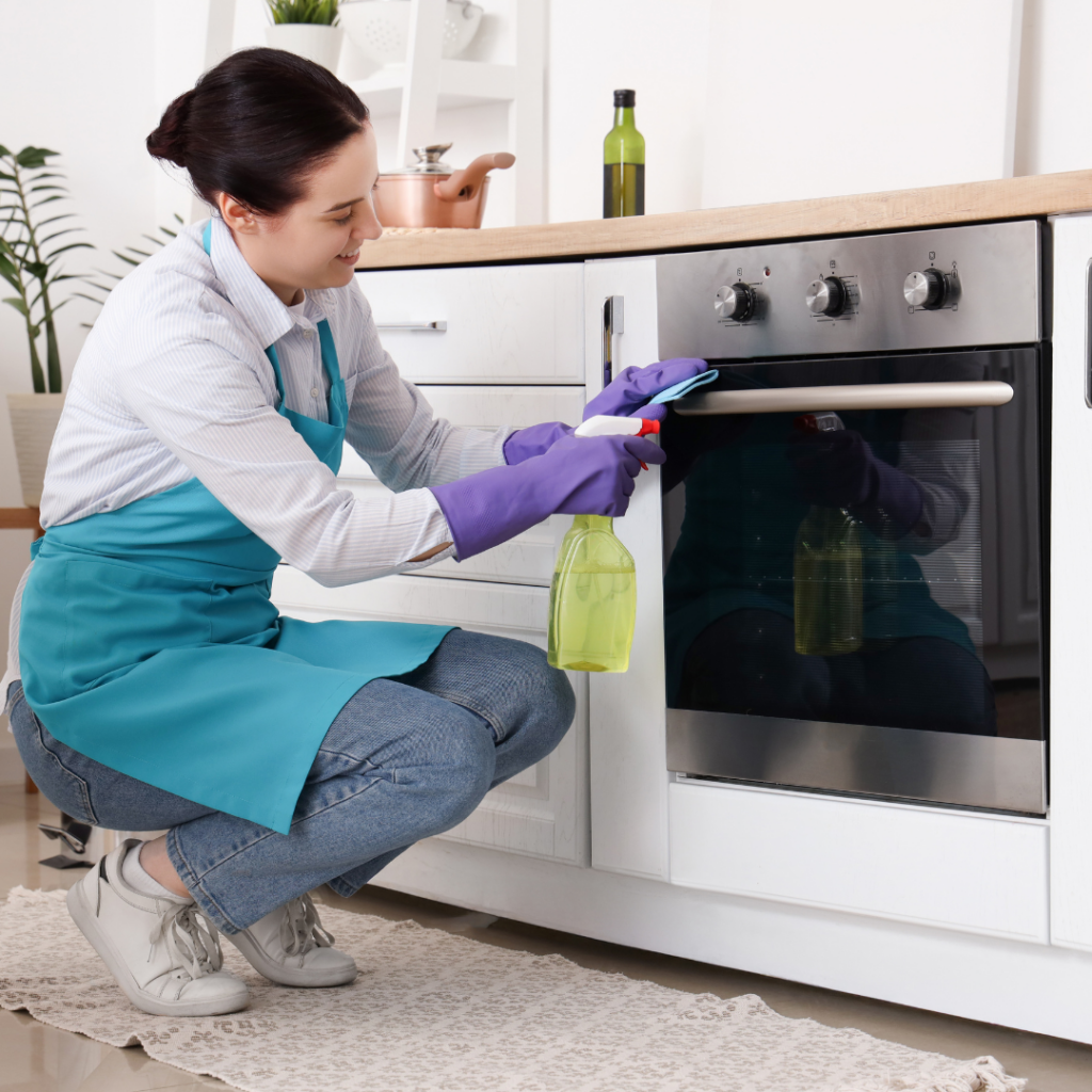 A woman with gloves on scrubbing her oven door.
