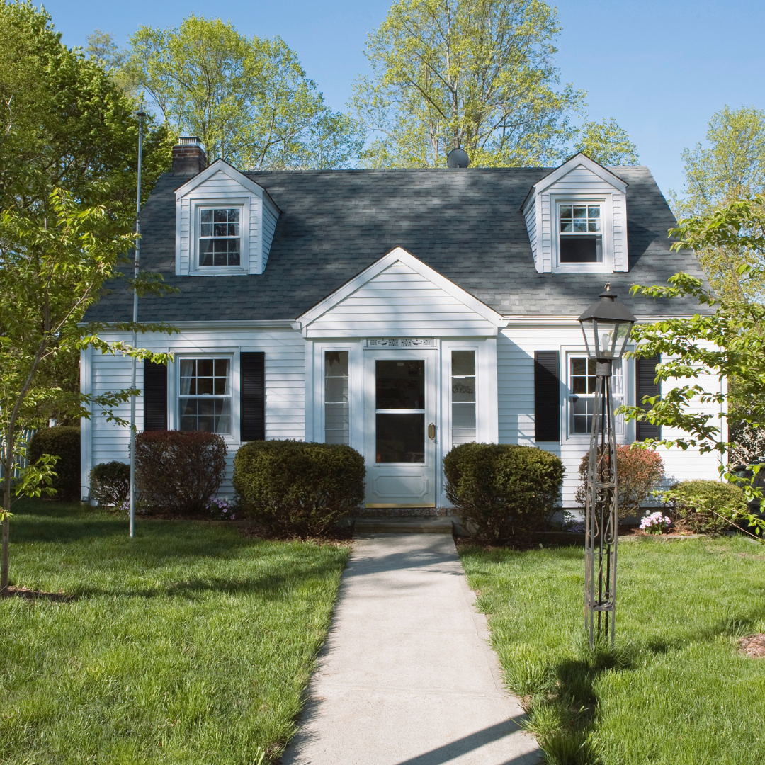 A charming, white house with a tidy front yard and plenty of curb appeal.