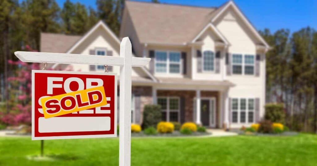 A two-story home with a sold sign in the front yard.