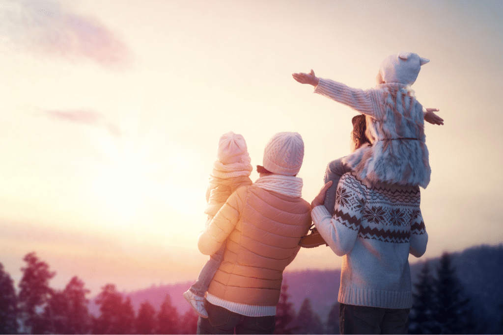 Happy family watching sunset outside in the winter.