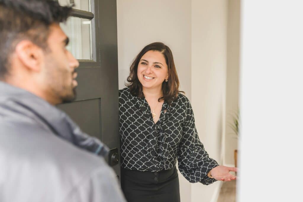 real estate agent welcomes a guest into an open house