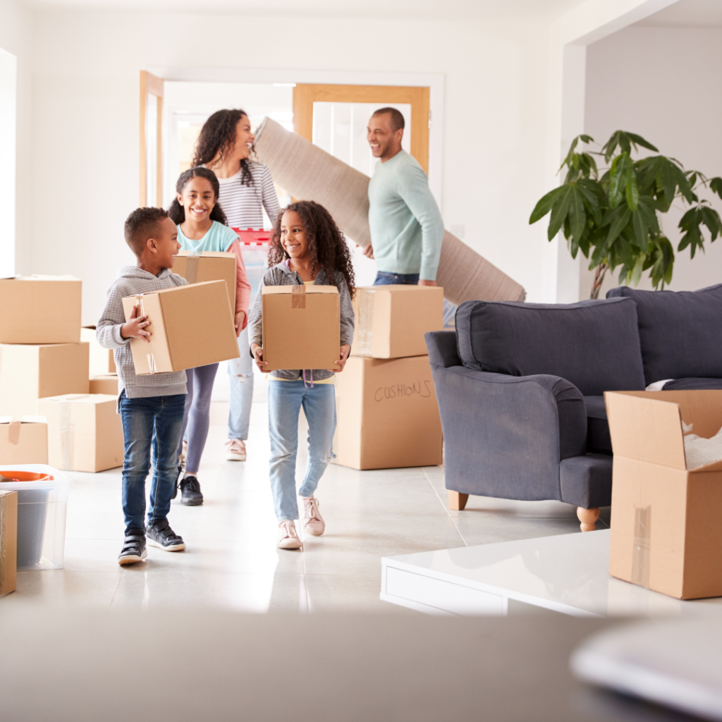 A family of five carrying boxes into their new home.