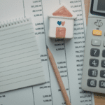 A work area with a paper, pencil, financial sheet, and calculator.